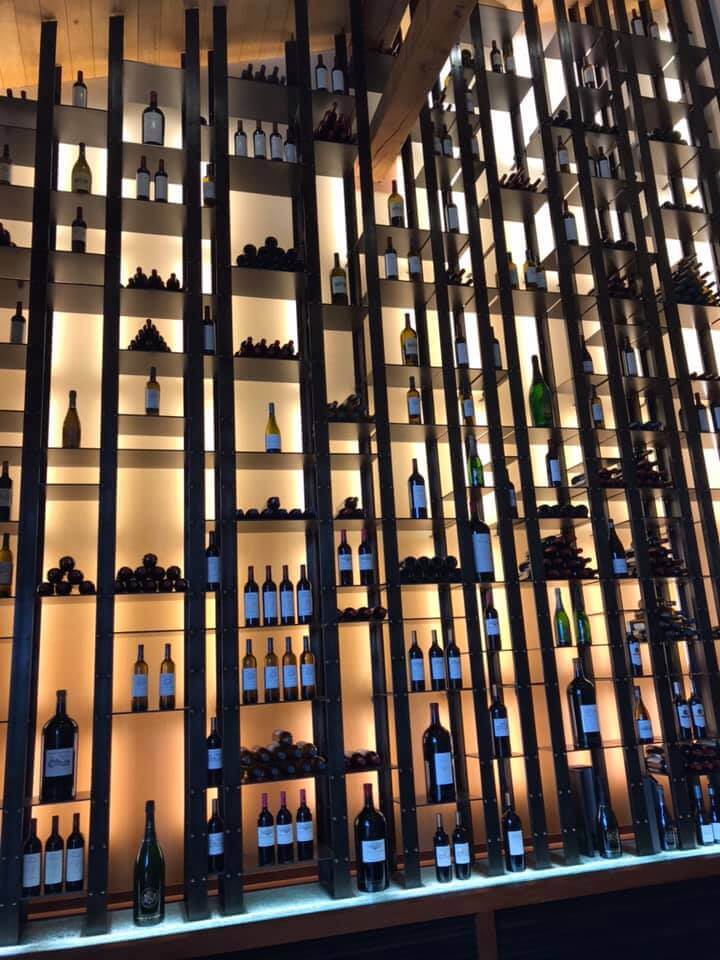 Etagère éclairée avec de nombreuses cases aux formes irrégulières pour présenter des bouteilles de vins